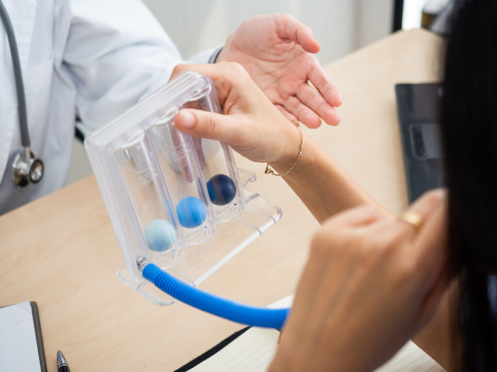 Patient blowing into a breathing rehabilitation device.